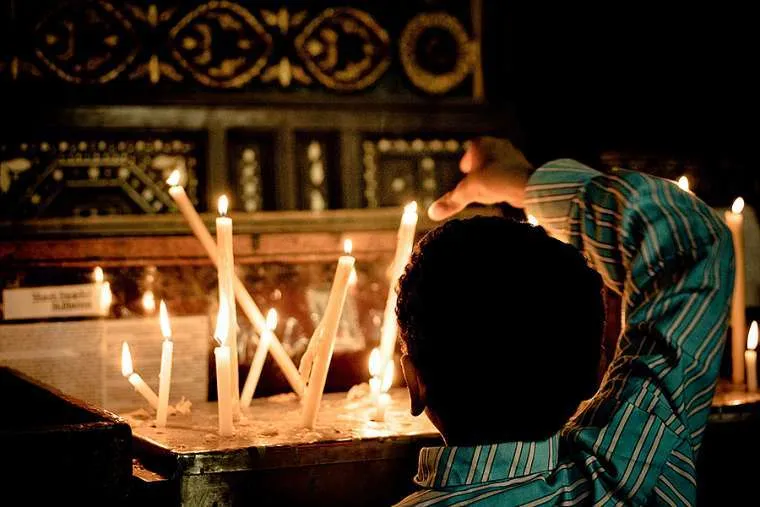 A Coptic Christian boy lights a candle at a church in Cairo. Credit: Christopher Rose via Flickr (CC BY-NC 2.0).