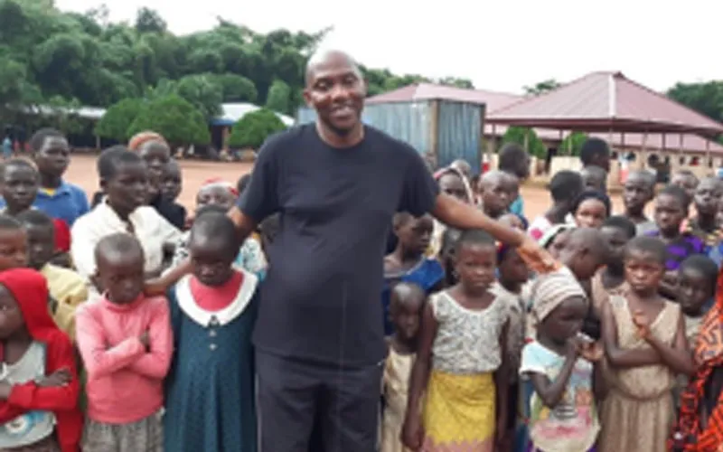 Pastor Solomon Folorunsho, Coordinator of Home for the Needy in Nigeria’s Benin State poses with a section of displaced children at the camp. Credit: Denis Hurley Peace Institue