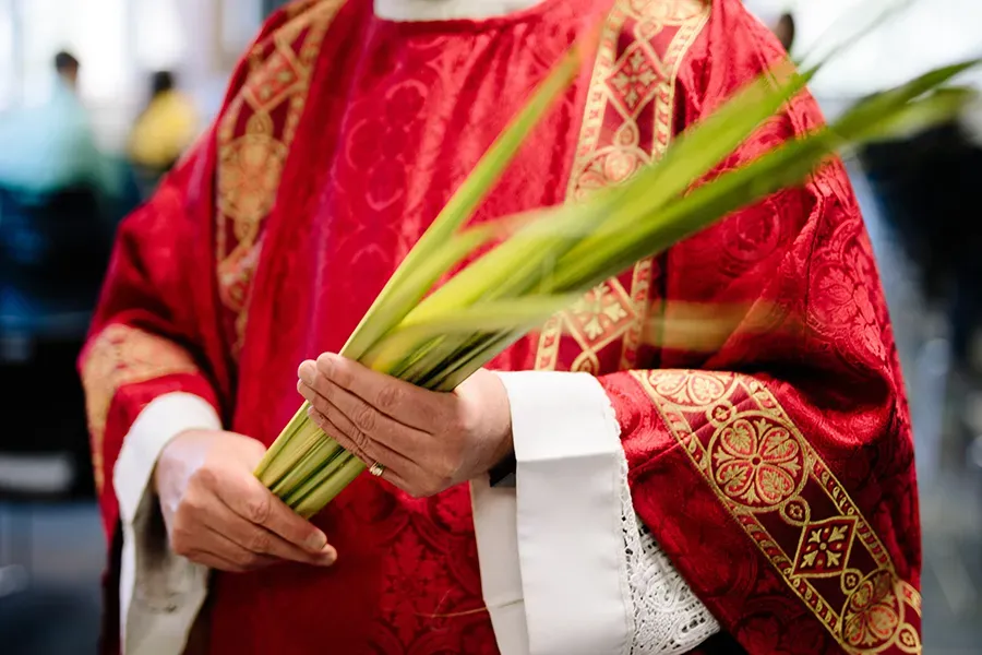 A priest holds palms on Palm Sunday. / Grant Whitty via Unsplash.