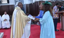 Fr. Bernard Hona Tonye hands certificates to couples with at least 15 years in marriage. Credit: Aïcha Marianne Kola