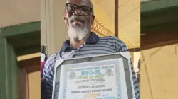Fr. Gabriel Luseni shows a certificate he was awarded for his contribution towards the promotion of education in Sierra Leone. Credit: ACI Africa