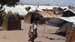 A woman walks outside makeshift houses in Mozambique. Credit: Denis Hurley Peace Institute