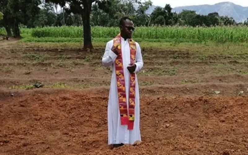 Fr. Sam Ebute prays over a mass grave in Nigeria. / Aid to the Church in Need (ACN)