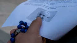 A faithful holds a rosary while touching an image of Pope Francis during prayers for the pontiff's recovery at Gemelli hospital on Saturday, Feb. 22, 2025. / Credit: Daniel Ibáñez/CNA