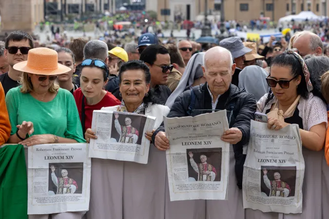 People reading the Osservatore Romano newspaper featuring the newly elected pontiff at St. Peter's Square for Pope Leo XIV's first Regina Caeli prayer on May 11, 2025