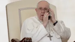 Pope Francis takes a telephone call during the May 17 General Audience. | Daniel Ibáñez/EWTN News
