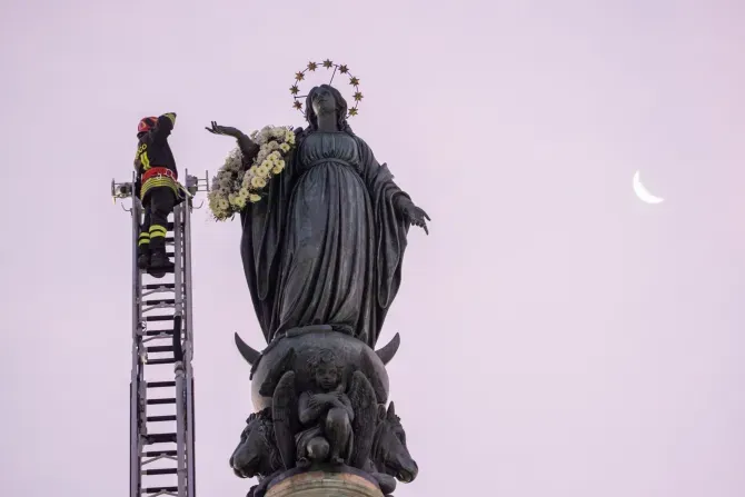 A firefighter scales a long ladder to the top of a nearly 40-foot-high column to pay tribute at dawn to the Blessed Virgin with a wreath of flowers on Dec. 8, 2023. | Credit: Daniel Ibanez/CNA