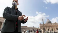 A pilgrim from Russia wears a mask and uses hand sanitizer in front of St. Peter's Basilica at the Vatican March 6, 2020. Credit: Daniel Ibáñez/CNA.