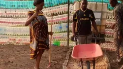 Fr. Innocent Akum Wefon pushing a wheelbarrow in his kitchen garden at St. Raphael Archangel Parish of the Catholic Archdiocese of Douala. Credit: 3650 Plastics At 10