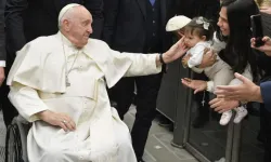Pope Francis, seated in a wheelchair, greets a child during the pope's general audience at the Vatican on Jan. 25, 2023. | Vatican Media